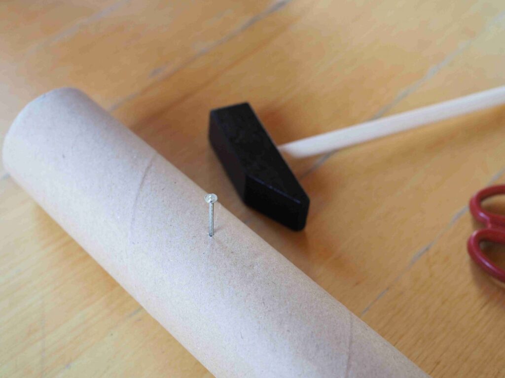 Kartonrolle mit Nagel und Hammer