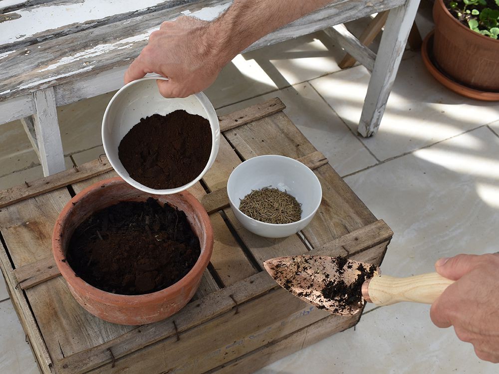 Hände mischen Bestandteile der Moorbeeterde in ein Gefäß