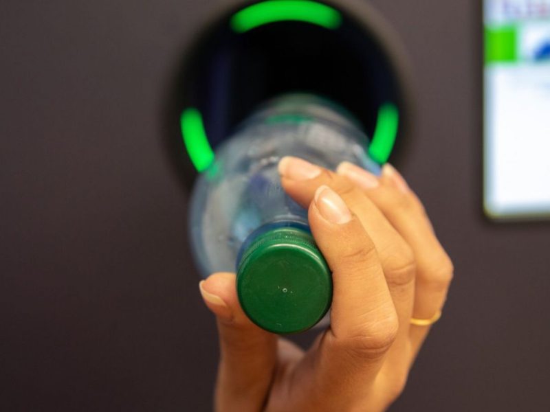 Person wirft Einwegpfandflasche in Rückgabeautomat