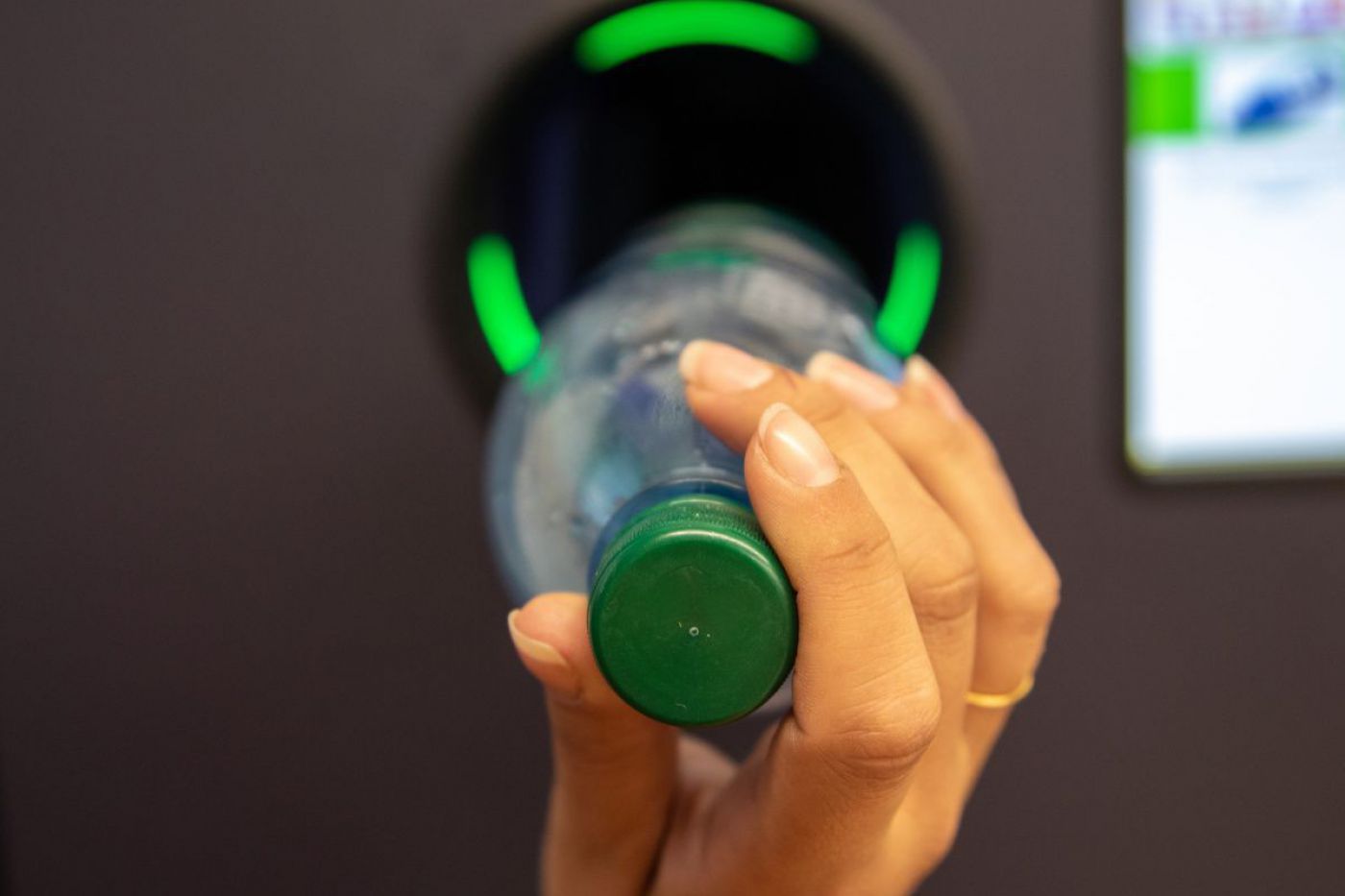 Person wirft Einwegpfandflasche in Rückgabeautomat