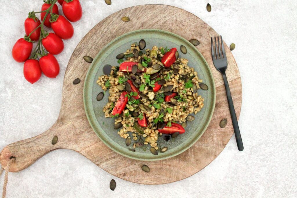 Dinkelreis-Salat mit Kernöl serviert auf Holzbrett