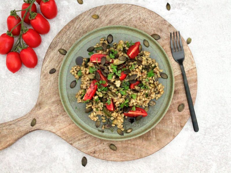 Dinkelreis-Salat mit Kernöl serviert auf Holzbrett