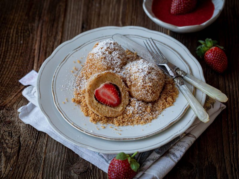 Drei Erdbeerknödel mit Brotbrösel und Puderzucker