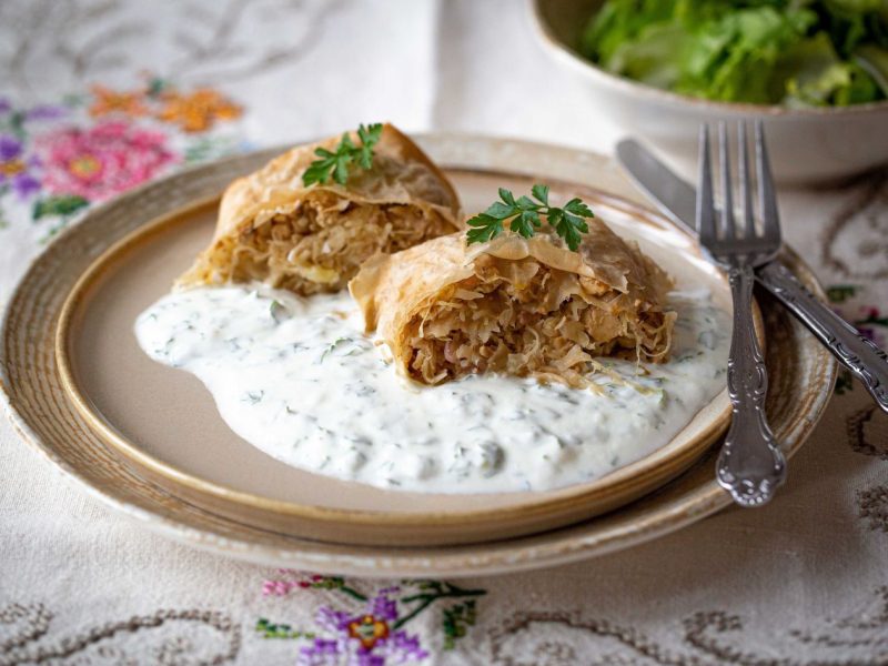 saftiger Krautstrudel, angerichtet am Teller mit Joghurtsoße