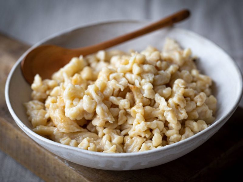 Frische Spätzle auf einem Teller mit Holzlöffel