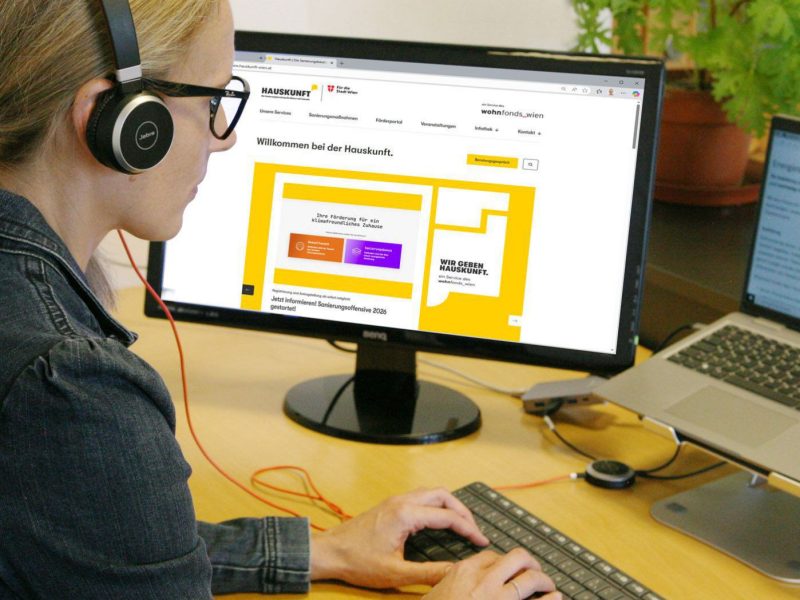Frau sitzt von Computern und tippt etwas ein.