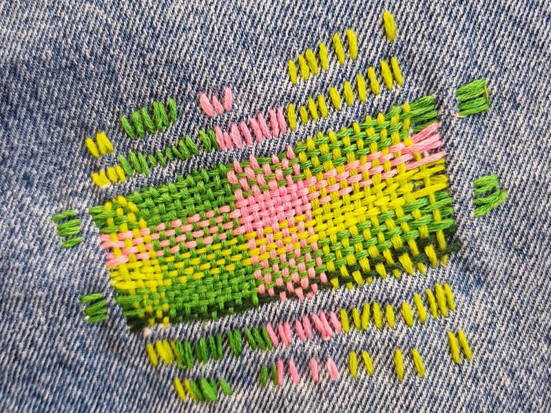 Mit bunten Fäden geflickte Jeans